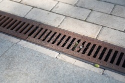 A rusty storm drain grate on the side of the road. Urban infrastructure, road protection from floods, heavy rains