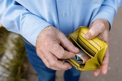 Senior man looks in his purse with Euro banknotes. Old man puts euro bills in his wallet. A wallet with the last money in the hands of an elderly man. A pensioner counts out the rest of his pension