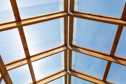 The roof of a greenhouse, barn or other agricultural building is made of transparent polycarbonate and wooden boards. bottom view