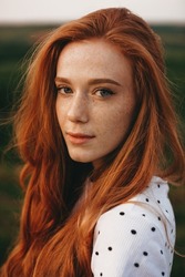 Close-up portrait of a redheaded woman with freckles looking at camera while posing outdoor. Natural beauty concept. Beautiful girl. Pretty young woman. Outdoor