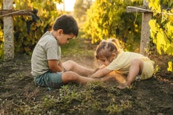 Brother with sister playing in vineyard digging a hole in the ground and getting dirty. Happy loving family. Summer vacation activities. Fun family. Happy
