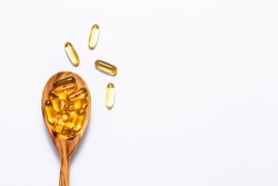 Omega 3 cod liver oil capsules in the wooden spoon on white background with copy space for your design. immunity support capsules. Health care concept.