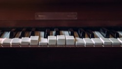 Close up shot to broken piano keys in abandoned house. An ancient musical instrument. Old broken disused piano with damaged keys Vintage Retro Filter. Distressed Piano made of wood. Selective Focus.