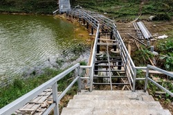 Construction of pedestrian bridge along the reservoir. The structure of construction of unfinished walkway bridge with ground column and iron railings over the reservoir. Pathway building over swamp.