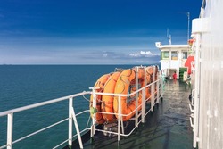 Orange inflatable lifeboats on ferry deck for emergencies and maritime accidents. Rescue boat, raft on the roof of a ferry.  Life boats on big ship on ocean sea cruise ship.Transportation and safety.