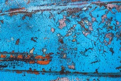Enamelled colorful cracked and peeling surface of old motorcycle. Rusty metal surface with blue cracked paint. Old motorbike paint cracks and rust. Rusty old metal. Vintage textured background concept