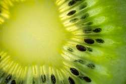 A slice of ripe juicy kiwi closeup. Detailed bright macro photo. The concept of fruit harvest, vegetarianism, useful healthy food, vitamins. Abstract food image.