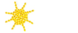 Creative concept vitamin D3, sunshine vitamin. Capsules are laid out in the shape of the sun on a white background. Copy space, minimalism, top view, horizontal banner. 