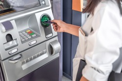 Young woman inserting a credit card to ATM 
