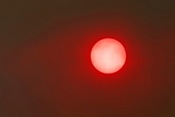 An angry red sun shines through smoke generated by an Arizona wildfire.