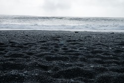 The Black sand beach of Reynisfjara, Vik and the mount Reynisfjall from the Dyrholaey promontory and Volcanic rock in the southern coast of Iceland with eroded stone arch visible in distance