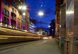 City street at night with a moving tram creating light trails. Taken in Manchester England. 