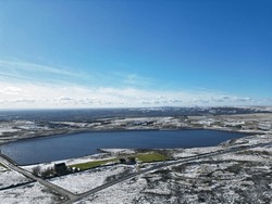 Aerial view of snow covered countryside with a blue lake and clear sky background. 
