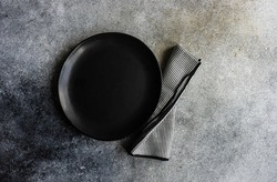 Minimalistic place setting with plate and napkin on concrete table