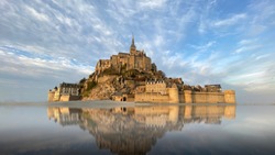 Beautiful Mont Saint Michel with water reflection and clouds on blue sky, France
