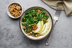 Fruit salad with pears, arugula, walnuts and Roquefort cheese. Delicacy appetizer in bowl on gray background