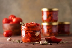 Sun-dried tomatoes in jar with spices and herbs. Autumn seasonal pickled or fermented colorful vegetables. Fall home food preserving or canning