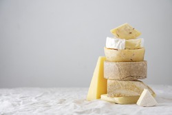 Various kind of cheese, traditional pieces of Spanish, French, Italy cheese. Light background with copy space, table with gray linen tablecloth