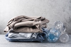 Stack of trendy modern clothes made from recycled plastic. Eco products and zero waste concept