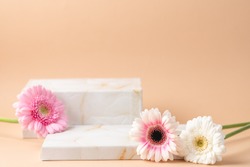 Empty podium boxes for presentation of cosmetic products. Marble boxes and pastel flowers  beige background