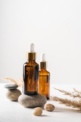 Serum, oil, acid in brown glass bottle on pebble pedestal. Side view, copy space. Spa products. Organic, bio, natural cosmetic. Beauty, skincare concept