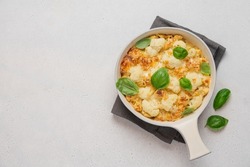 Mac and cheese with cauliflower. Baked pasta with cheese and cabbage in ceramic pot on white background. American cuisine concept