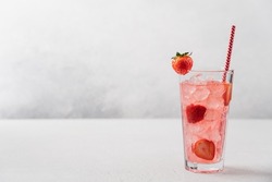 Strawberry lemonade with ice in tall glass on light gray background. Berry refreshing summer drink with straw