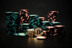 Bitcoin coins on the background of a slide of casino chips on a black background. Bitcoin casino game. Cryptocurrency excitement. Bet on bitcoins.
