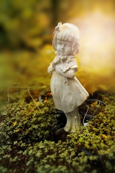 Sculpture of little girl in garden, background for Valentine's day. Selective focus and color toned.