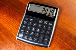 Electronic calculator isolated on a dark wood backgroud displaying 2019