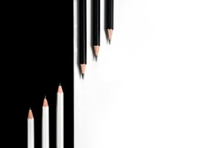 Composition with black pencils on a white background and white pencils on a black background lying next to it. Concept school supplies
