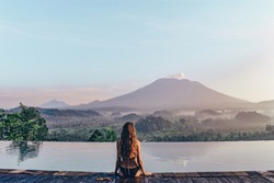 series traveling girl in Asia. beautiful girl with long dark hair in swimming suit in beautiful nature place in Bali, posing near swimming pool with volcano Agung view