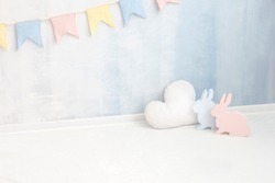 Pastel baby background in soft light blue and pink colors with rabbit bunny cloud figure near paint wall in child room. Easter newborn concept greeting card