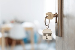 Key with keychain in a house shape in the door keyhole. Buy new home concept. Real estate market.