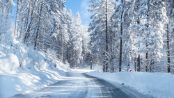 Snowy winter road in a mountain forest. Beautiful winter landscape.