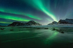 Northern Lights on the night sky. Aurora Borealis over Skagsanden beach on Lofoten Islands. Northern Norway. Wintertime starry sky.