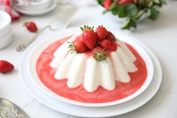 Panna cotta, a molded chilled Italian dessert, made of cream, sweetened with sugar, flavored with vanilla and gelatin, served  with ripe red freshly picked strawberries. White background, copy space