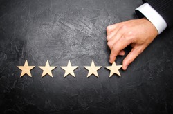The businessman's hand in the suit holds the fifth star. Get the fifth star. The concept of the rating of hotels and restaurants, the evaluation of critics and visitors. Quality level, good service.