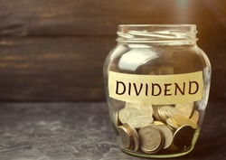 Glass jar with the word Dividend. A dividend is a payment made by a corporation to its shareholders as a distribution of profits. Concept business finance and investment. Saving money. Dividend tax