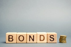 Wooden blocks with the word Bonds and coins. A bond is a security that indicates that the investor has provided a loan to the issuer. Equivalent loan. Unsecured and secured bonds