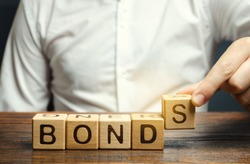 Businessman puts wooden blocks with the word Bonds. A bond is a security that indicates that the investor has provided a loan to the issuer. Equivalent loan. Unsecured and secured bonds.
