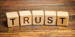 Wooden blocks with the word Trust. Trust relationships between business partners, friends, relatives. Respect and authority. Confidence in a person. Reliable partner