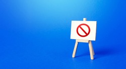 Easel with the prohibition sign NO on a blue background. Restricted area. Restrictions and Sanctions. Out of stock. Ban and Embargo. Failed strategy. Inaccessibility, taboo. Blocking.