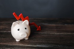 Sad piggy bank and down arrow. Savings and reserves decrease. Inflation, depreciation of assets. Falling income, lower wages. Falling GDP. Economic recession, crisis. Capital flight, worsening economy