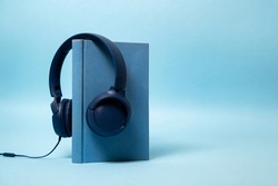 Audio book concept , blue book with headphones hanging on 