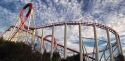 Panoramic view of red roller coaster track with beautiful cloudy sky