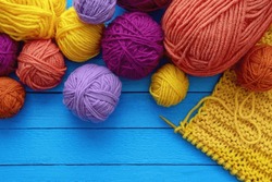 Hobbies and knitting concept. Colorful balls and skeins of wool and  knitting needles on blue background. Copy space