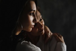mom and daughter, embrace, on a dark background with natural light