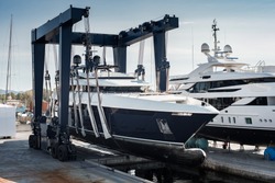Super Yacht hauled out in shipyard, being lifted by industrial crane for refit or maintenance yard period 