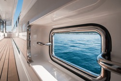 Nautical detail of a fairlead on a superyacht, with view over to the water and the corridor with teak deck on a sunny day